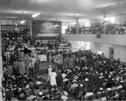 Black and white photo of mourners filling Roberts Temple